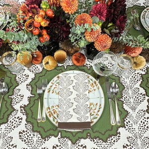Decorative table setting with autumn-themed centerpiece, plates, and cutlery on a patterned tablecloth. Thanksgiving table, embroidered placemats.