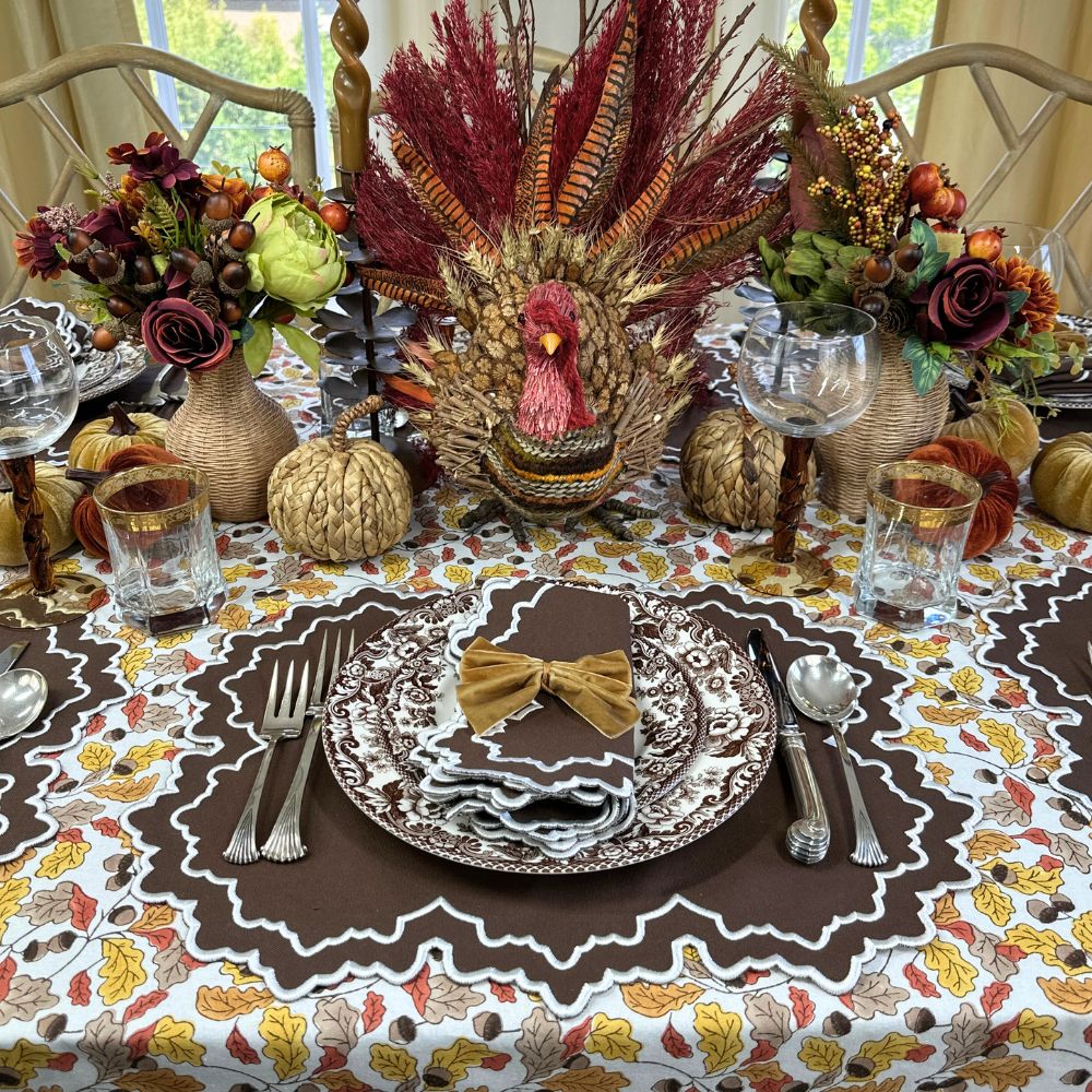 Thanksgiving table setting with turkey centerpiece, fall decorations, and place settings. Acorn leaves hand block printed tablecloth, Whitley placemat and napkin and velvet gold napkin bow ties