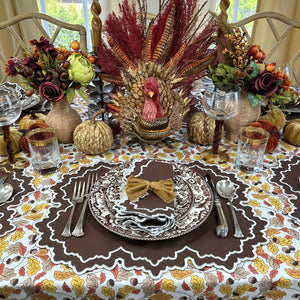 Thanksgiving table setting with turkey centerpiece, fall decorations, and place settings. Acorn leaves hand block printed tablecloth, Whitley placemat and napkin and velvet gold napkin bow ties