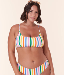 Model confidently wearing Andie Swim's Fiji Bikini Top in Rainbow Stripe, designed with eco nylon fabric and a flattering scoop neckline.