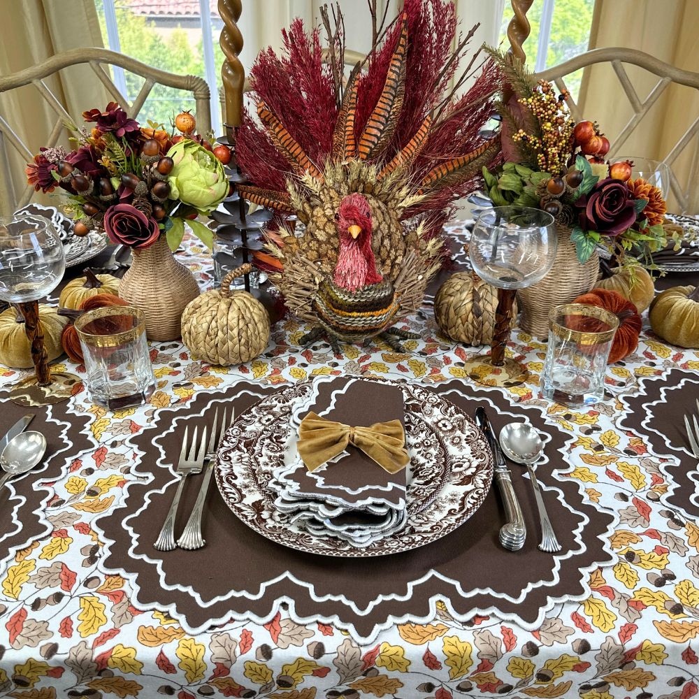 Thanksgiving table setting with turkey centerpiece, fall decorations, and place settings. Acorn leaves hand block printed tablecloth, Whitley placemat and napkin and velvet gold napkin bow ties