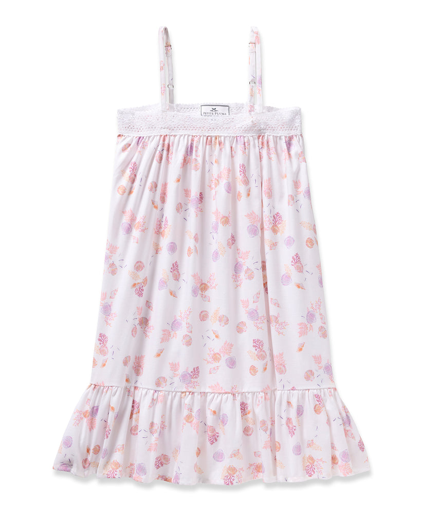 Enjoy the elegance of Petite Plumes Girls Twill Lily Nightgown in Seashell Splendor—a white sleeveless dress boasting pink and purple floral and fruit patterns, yarn-dyed cotton, a lacy trim top, and a ruffled hem for luxurious sleep.