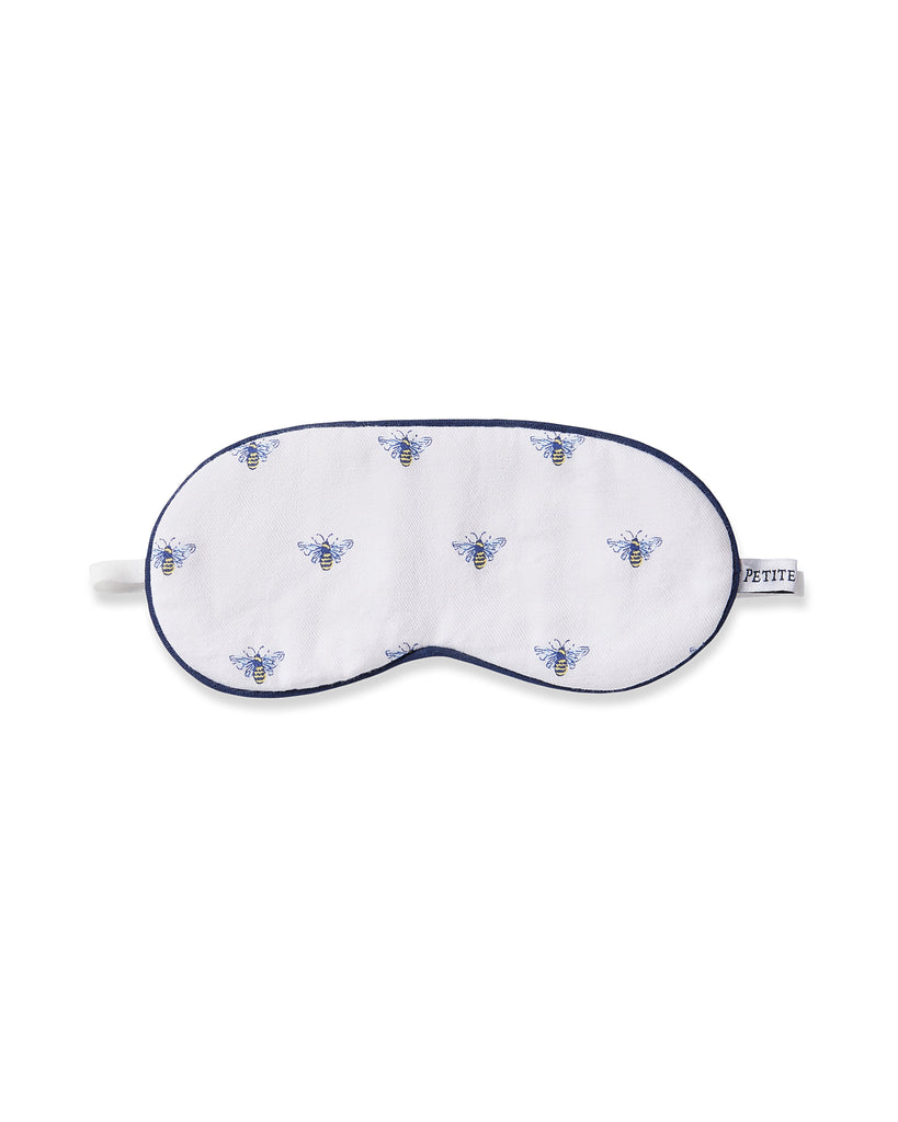 The Petite Plume Kids Twill Sleep Mask in Buzzing Bees is a white mask with blue and yellow bees pattern, dark blue trim, an elastic strap for comfort, and offers monogramming for personalization.