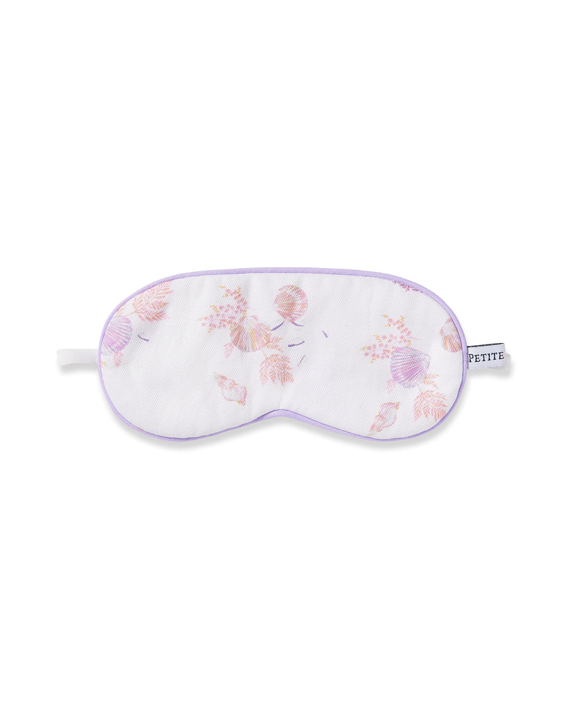 The Kids Twill Sleep Mask in Seashell Splendor by Petite Plume features a white design with a soft purple border and small floral patterns in pastel pink and purple. A side tag reads PETITE, making it perfect for those who value intricate details in their bedtime accessories.