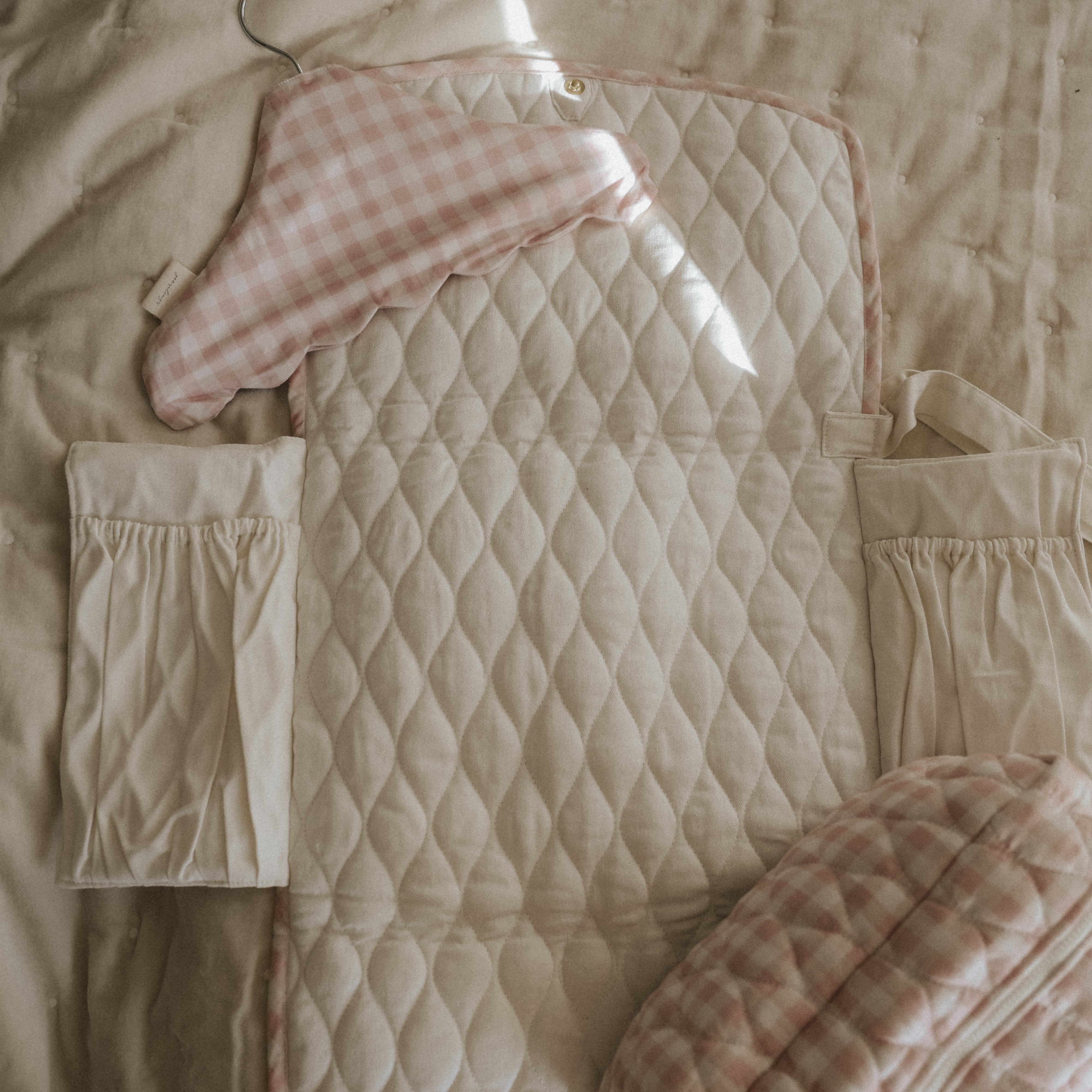 Portable Changing Pad in Pink Gingham. Inside is Ivory with pocket detail. Hanger and Pouch in Pink Gingham also displayed in photo