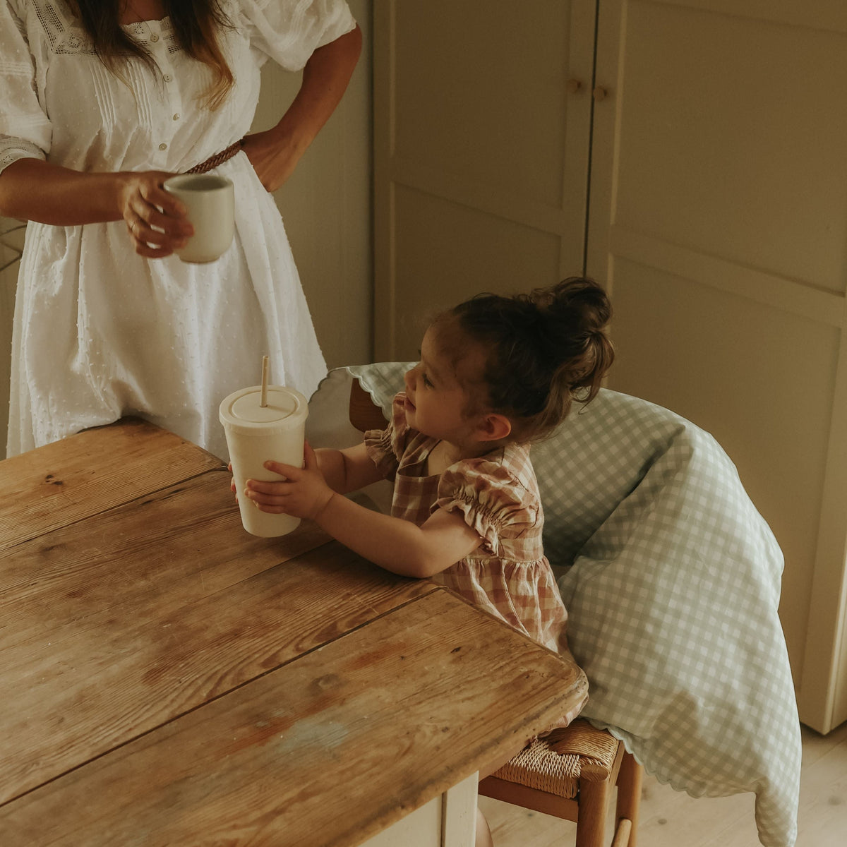 Green Gingham Baby Duvet hanging off chair with child sitting at table