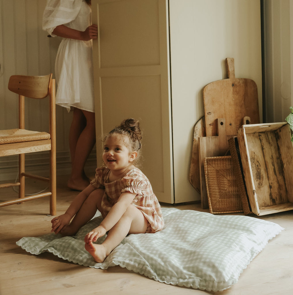 Green Gingham Toddler Duvet laying on the floor with child sitting on top