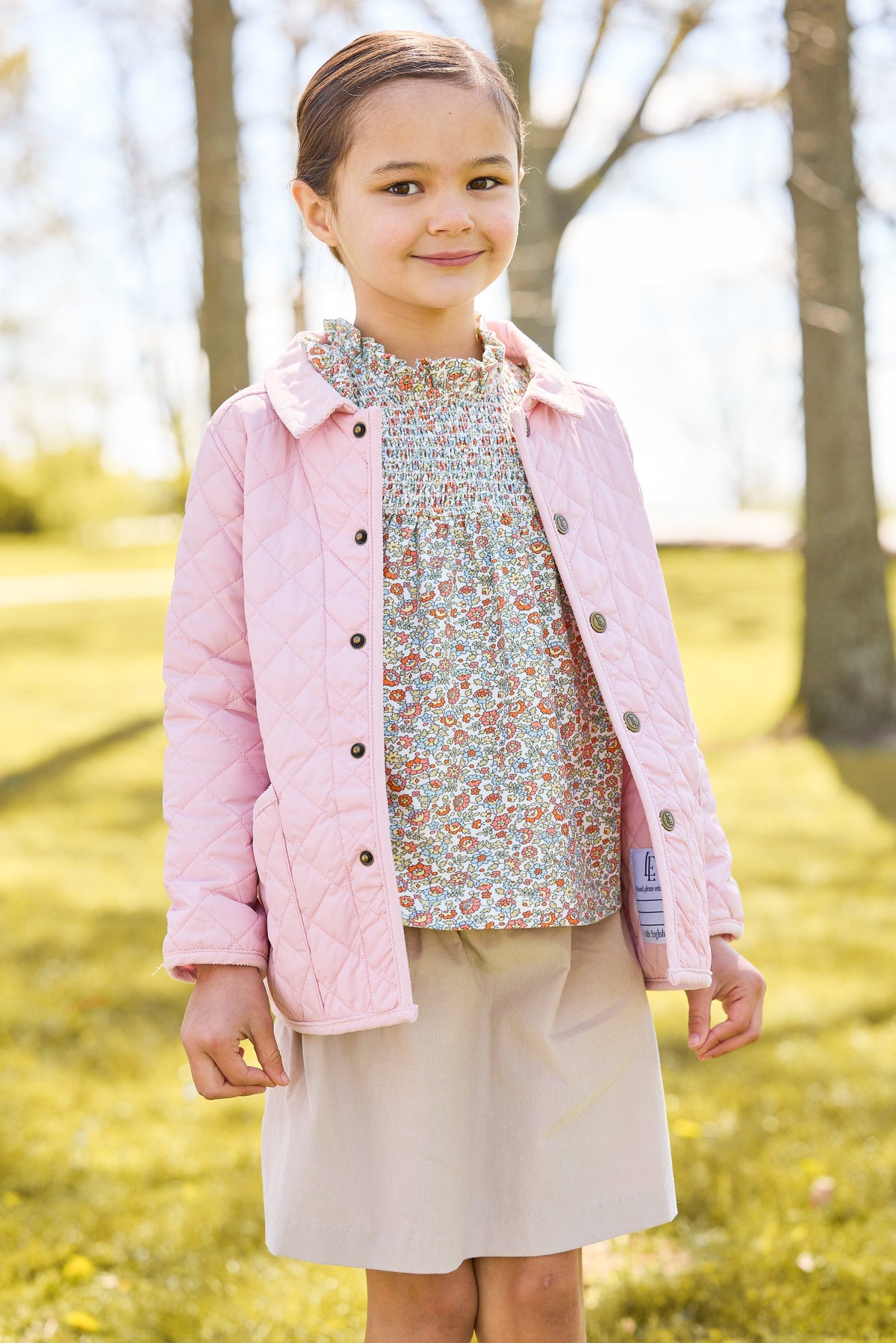 Little english classic childrens clothing, quilted jacket in light pink, hallie top in orange, blue, and green james floral, paperbag bow skirt in stone corduroy