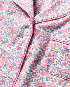 Close-up of Petite Plumes Womens Pima Crop Set in Fleurs de Rose, made of Pima cotton fabric with pink piping, small pink and blue flowers, green leaves, white buttons, and a pocket—perfect for enhancing your bedtime ritual.