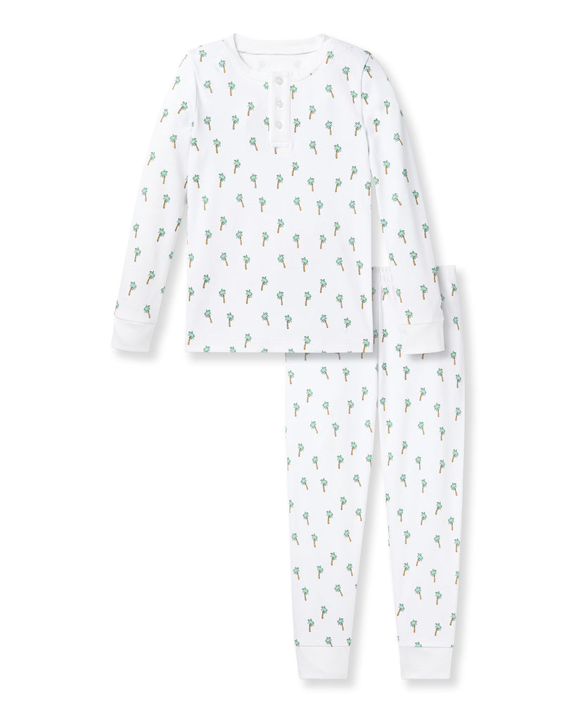 The Kids Pima Snug Fit Pajama Set in Palmier by Petite Plume features a white long sleeve top and pants with small green and orange dinosaurs, crafted from soft Pima cotton for comfort, complete with a round neckline and buttons.
