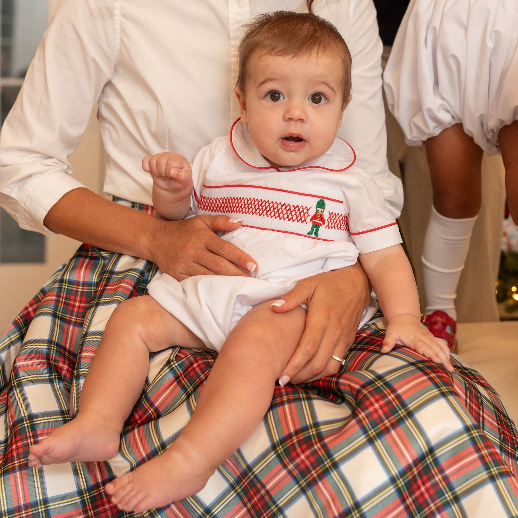 White baby boy holiday bubble with red toy soldier smocking and Peter Pan collar, Henry Duvall's Charlie Bubble in cotton poplin for Christmas celebrations