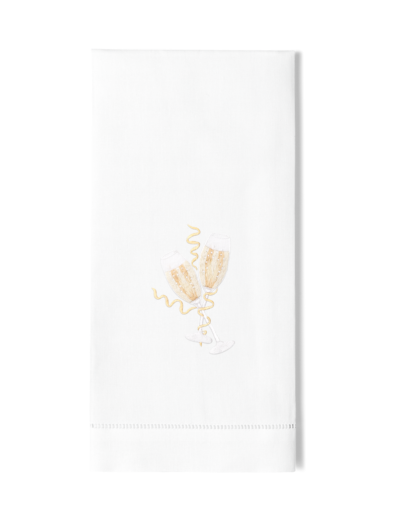 A white hand towel with a hemstitch. Two toasting champagne glasses are embroidered in the center.