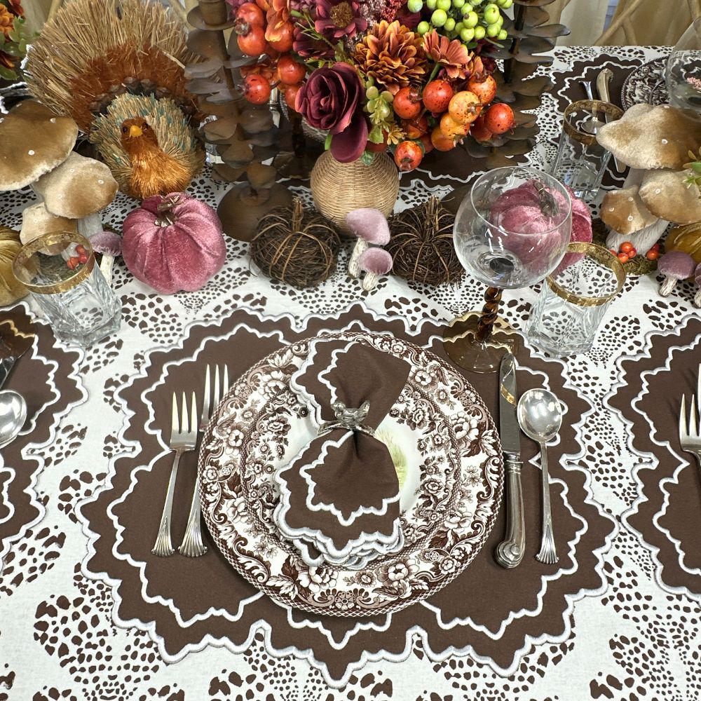 Decorative table setting with pumpkins, flowers, and cutlery on a patterned tablecloth. Luxury embroidered placemat and and napkin in cooca and turkey silver napkin ring