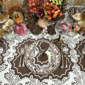 Decorative table setting with pumpkins, flowers, and cutlery on a patterned tablecloth. Luxury embroidered placemat and and napkin in cooca and turkey silver napkin ring