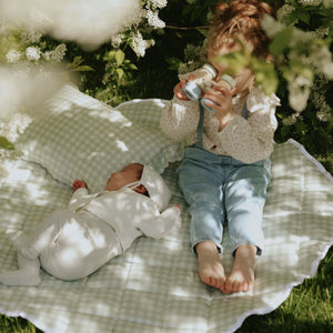 Picnic Gingham Green Playmat with a baby sleeping and toddler playing