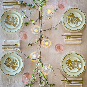 Bird's eye view of a spring tabletop featuring Caskata's Gold Arbor canapé plates on Grace Gold buffet plates around an assortment of Quinn mouth-blown glassware and a flowering branch centerpiece.