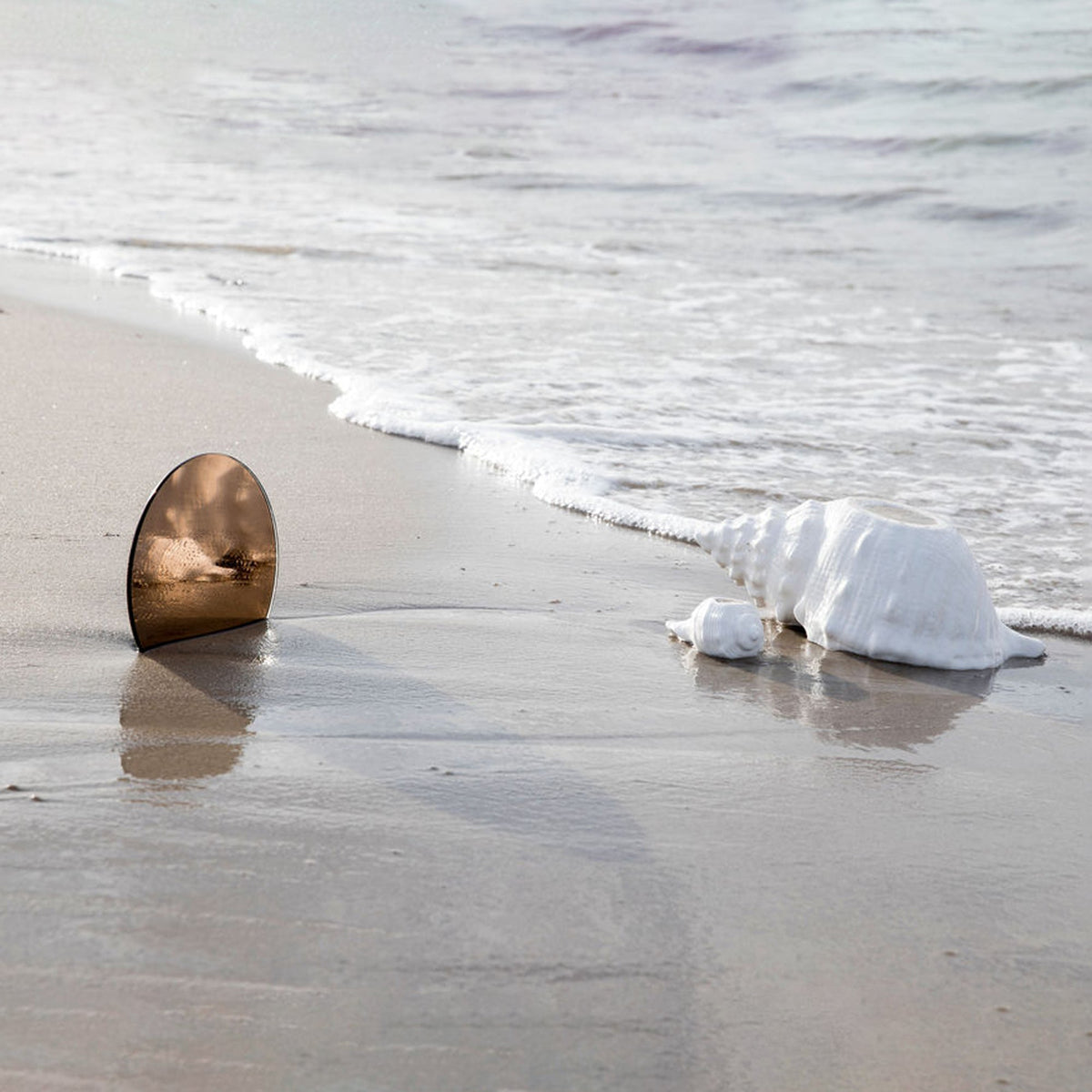 Side view of Awa Bowl in White, Ceramic showcasing its spirally twisted shell shape on a beach