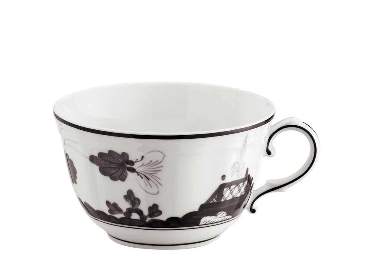 Side view of Oriente Italiano tea cup showing white porcelain with black floral motif and curved handle on white background