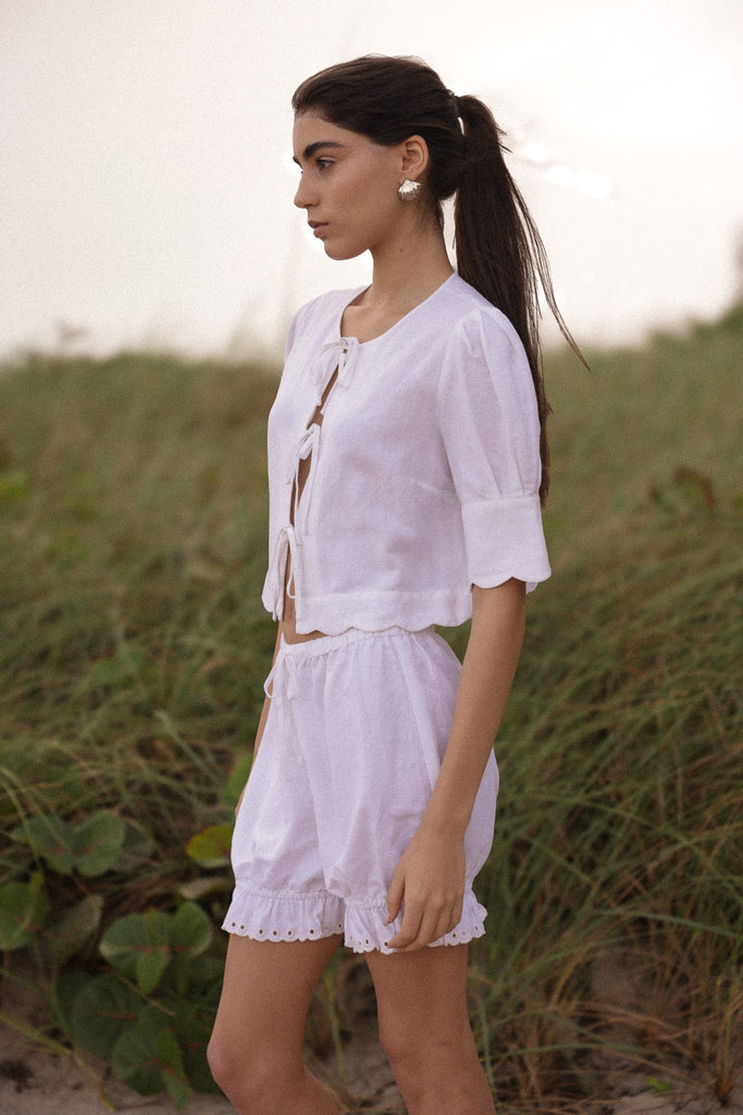 Woman in a white linen outfit standing in a grassy field.