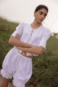 Woman wearing a white outfit with ruffled details in a natural setting