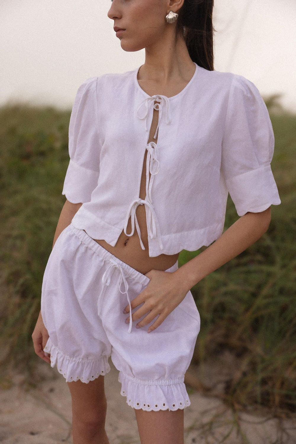 Front view of Bloomer Short in White on model showing adjustable drawstring waist and eyelet ruffle hem in outdoor setting
