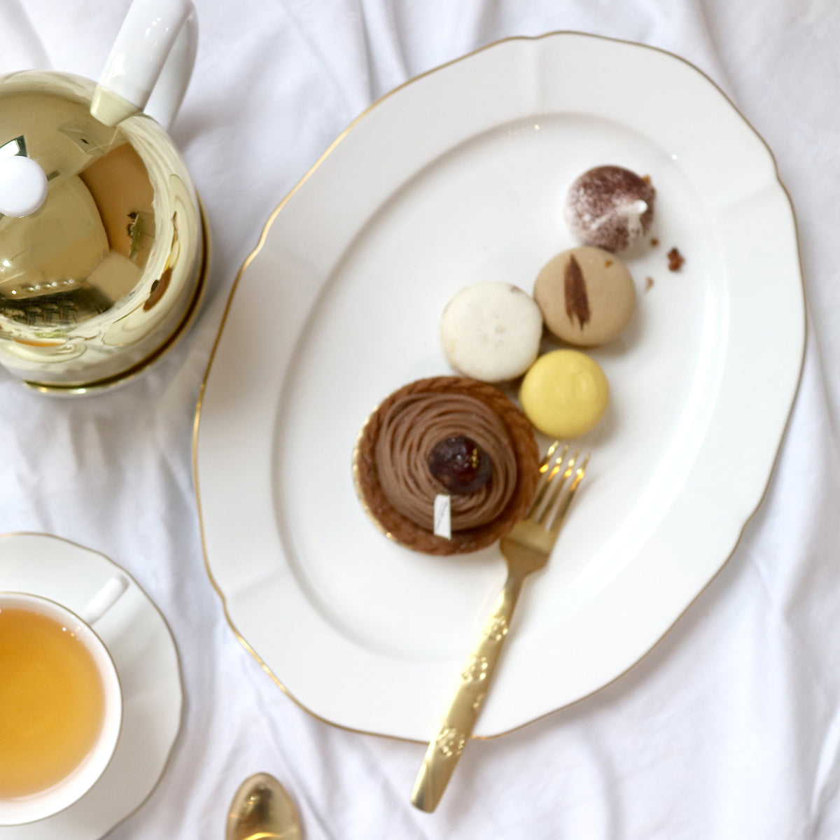 Overhead view of Amelie Brushed Gold oval platter showcasing scalloped edges and hand-painted 24K gold rim with desserts