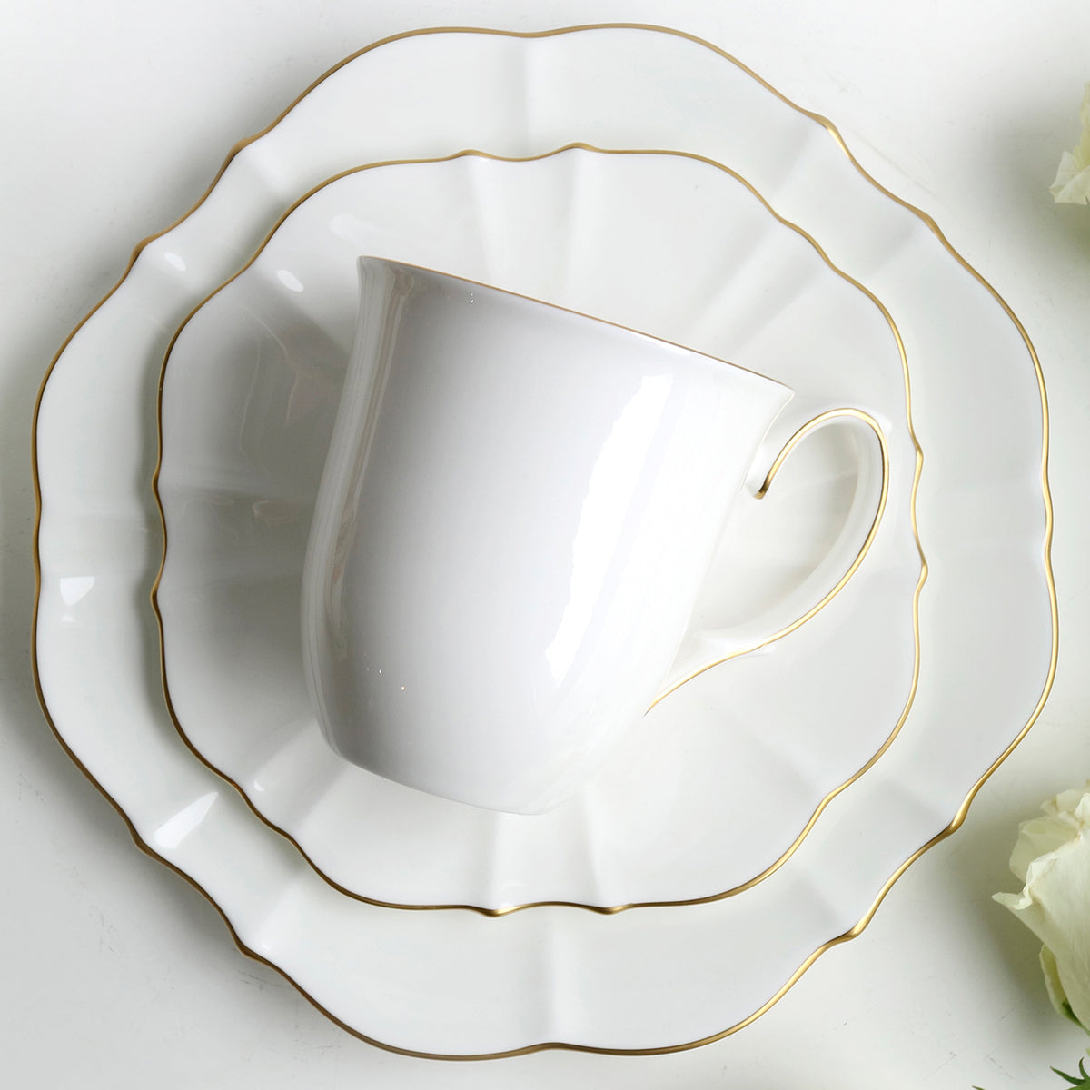 Top-down view of Amelie Brushed Gold mug on matching scalloped plates showcasing hand-painted 24K gold rims on white bone china