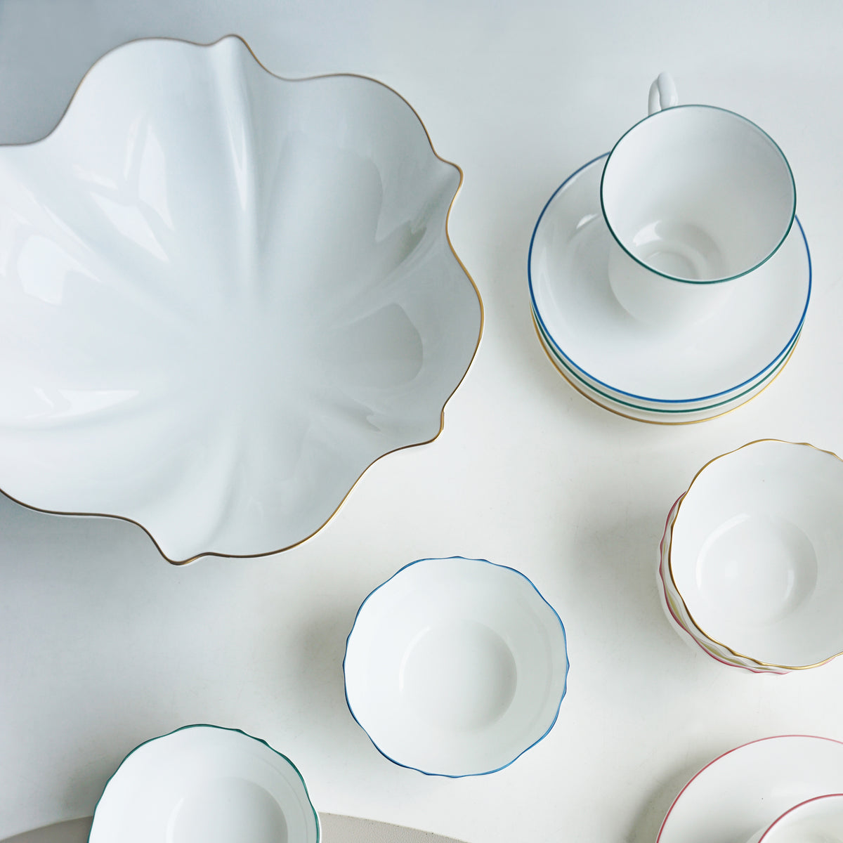 Overhead view of Amelie Brushed Gold Serving Bowl showcasing scalloped edges and hand painted 24K gold rim among white tableware