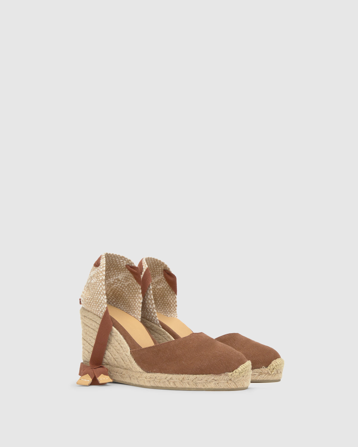 Three-quarter view of Carina 8 wedge in pecan with lace-up ties, cotton upper and braided jute sole on gray background