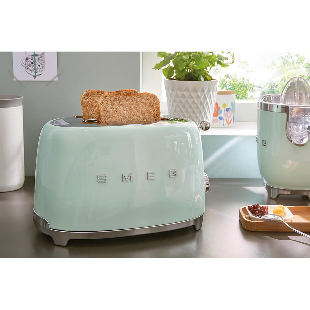 Three-quarter view SMEG 4-slice toaster in pastel mint, two extra-long slots with two slices of toast on countertop