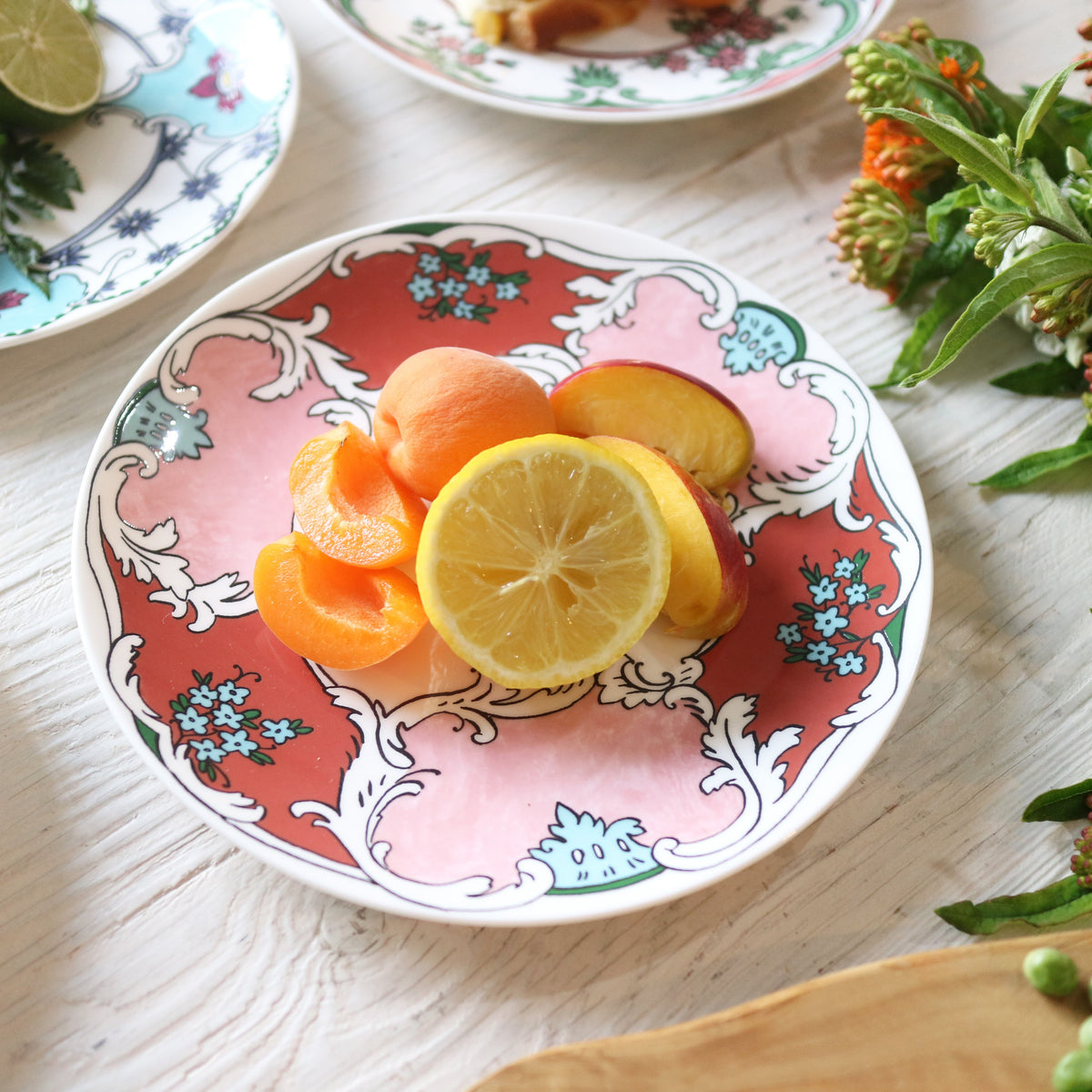 Angled view of Always Camille 8 inch Salad Plate showcasing colorful hand painted floral decals with citrus on a wooden table