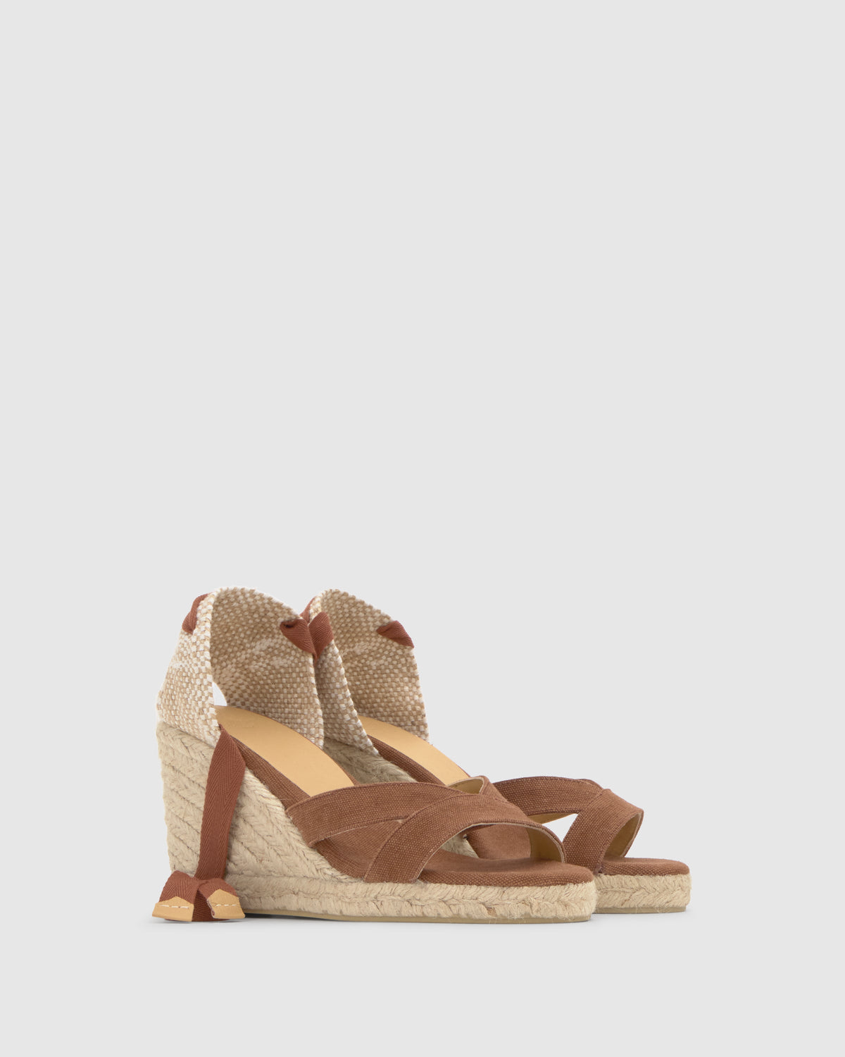 Three-quarter view of Bailey 8 wedge espadrille sandal in Pecan showing jute wedge, crisscross cotton straps and ankle-tie ribbons on light gray background