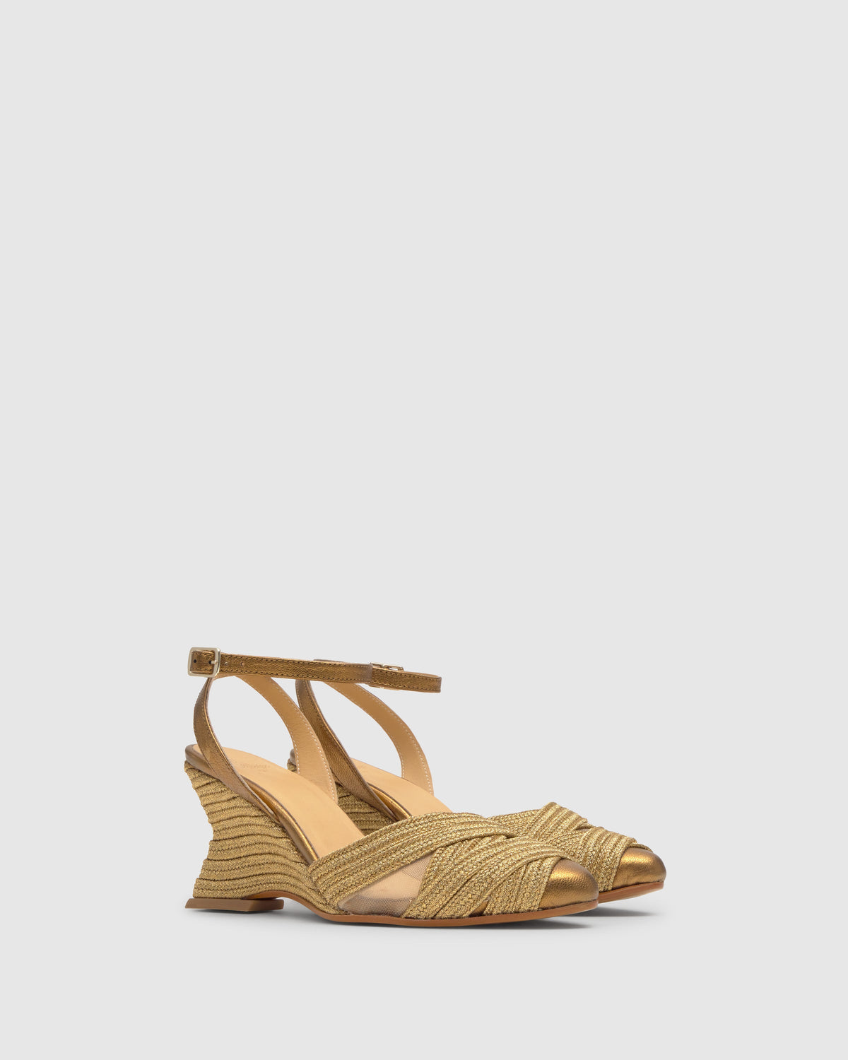 Three-quarter view of Joy espadrille wedge in old gold with braided metallic straps and jute-wrapped heel on gray background