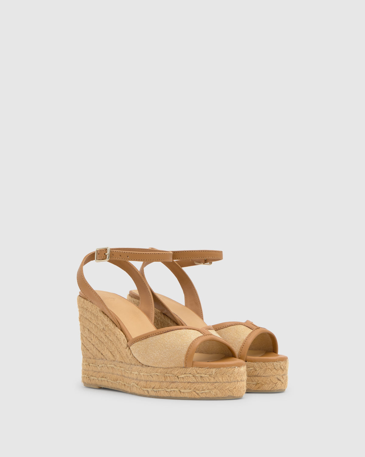 Three-quarter view of Brigitte 8ED wedge sandal in ochre with hand-stitched jute wedge and ankle buckle on light gray