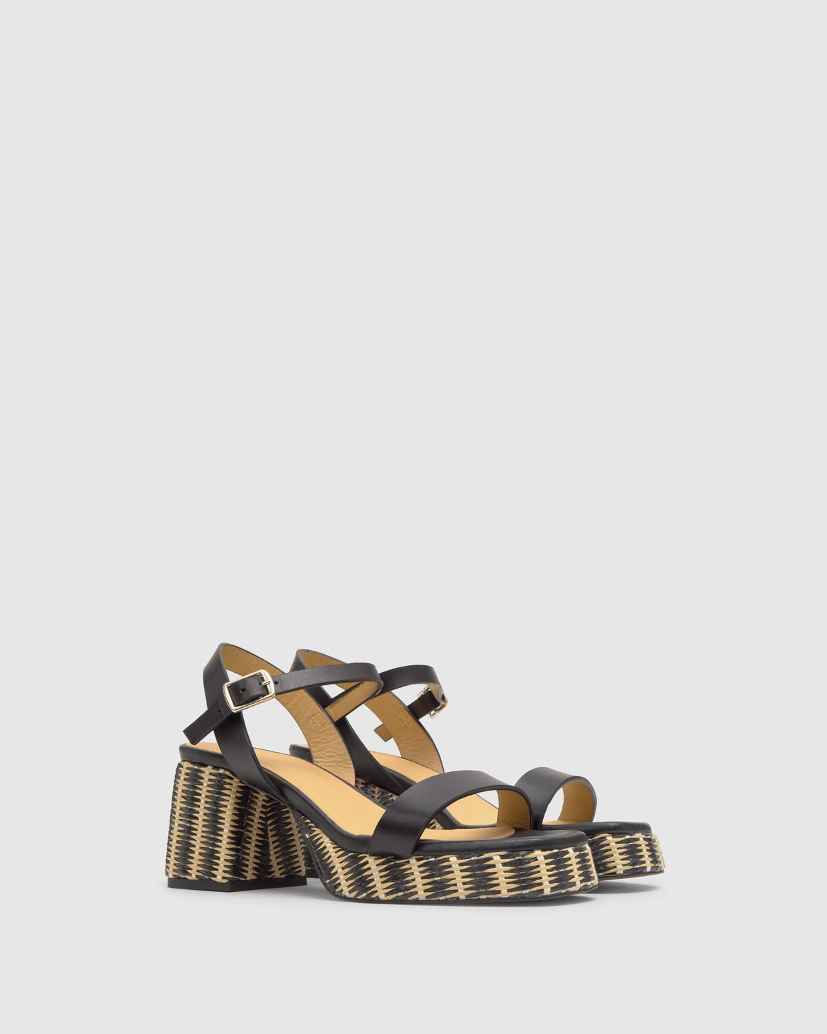 Three quarter view of Voramar sandal with black leather straps, buckle ankle strap and woven jute wrapped block heel on gray background
