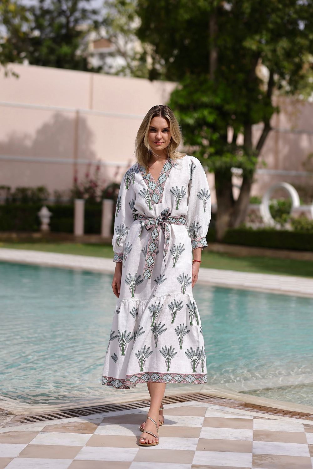 Front view of Capri Maxi Dress in Blue Palm showing belted waist, V-neck, 3/4 sleeves, and palm print by pool