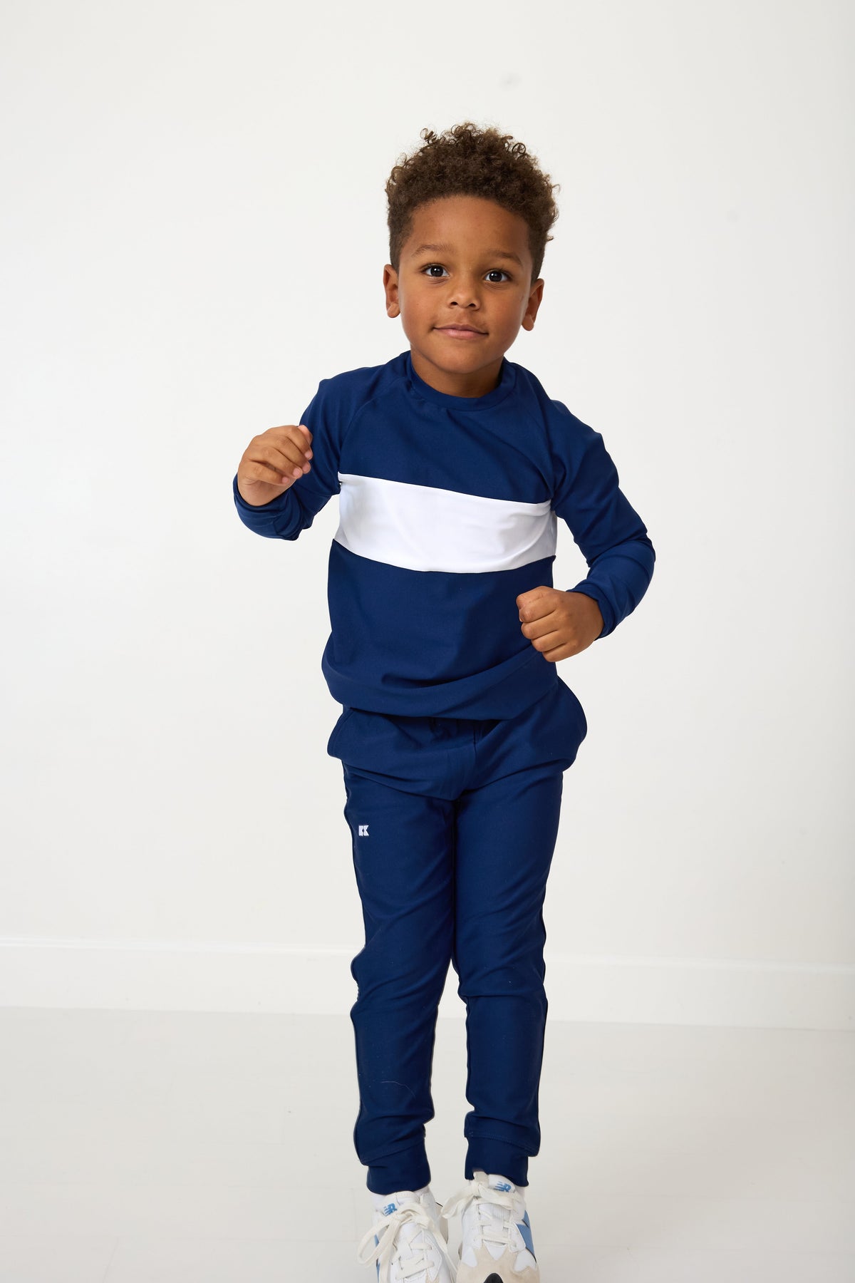 Front view of navy pullover on child model showcasing wide white chest stripe and crewneck against white studio background
