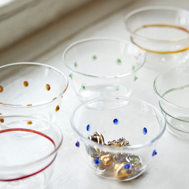 Close-up of Green Pom Bowl showcasing green dot detailing with other glass bowls in background