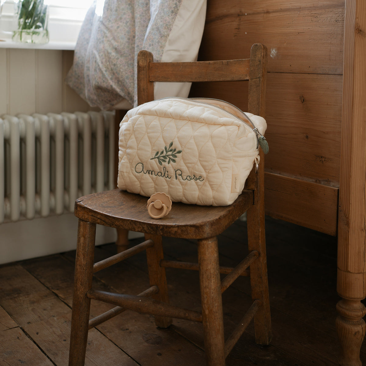 Toiletry Pouch in Ivory sitting on top of wooden chair with wooden dresser in the background