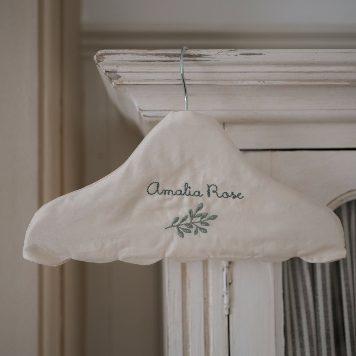 Children's Hanger in Ivory hanging off top of armoire