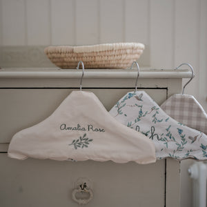 Children's Hanger in Ivory, Secret Garden, and Beige Gingham hanging off top of dresser