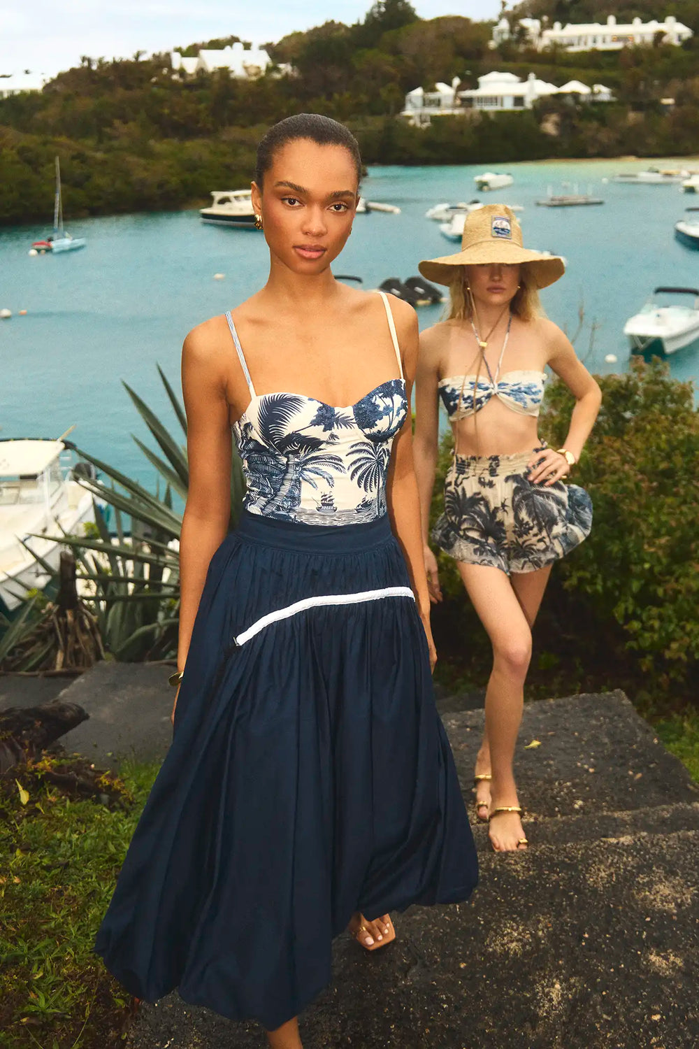 The Allegra Skirt in Navy paired with Nevis One Piece in Bermuda Toile in front of ocean. 