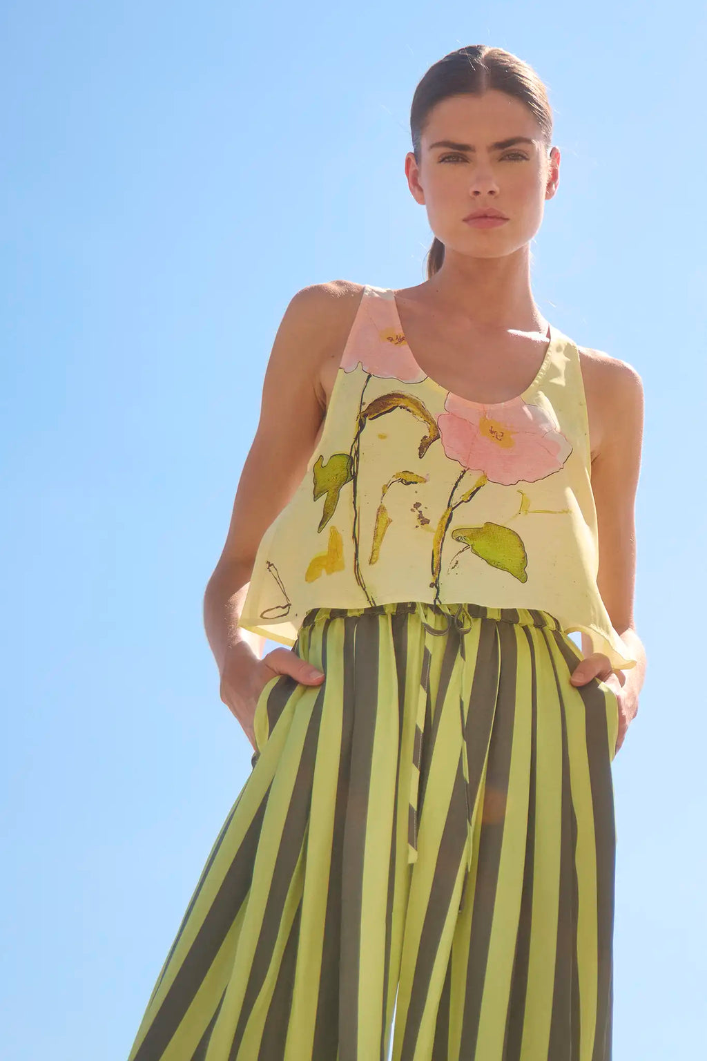 The Carsyn Tank in Quiet Bloom paired with Cyprus Pant in Evergreen Stripe in front of a blue sky.