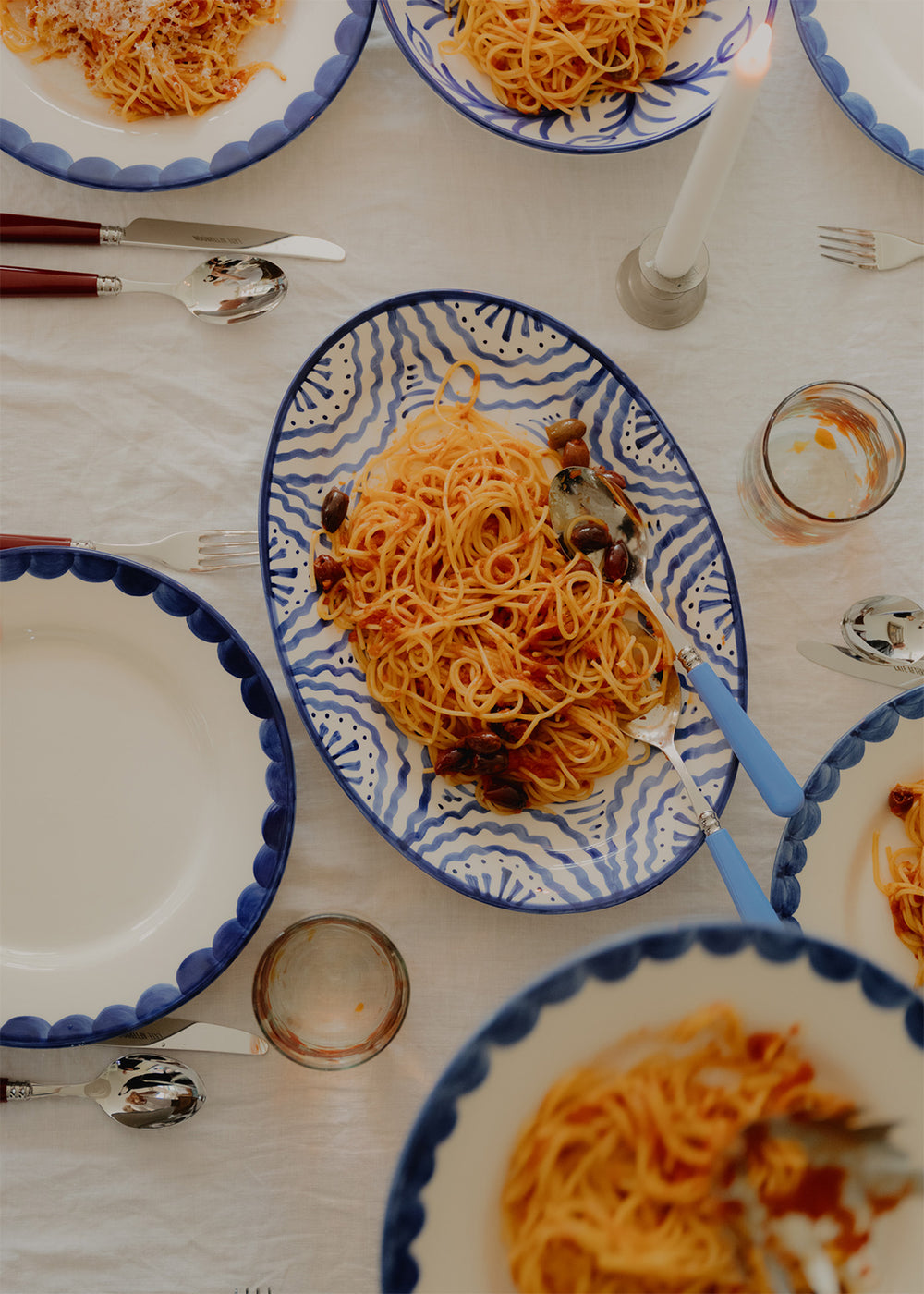 Top-down view of Late Afternoon large blue oval serving platter with hand-painted wavy pattern and spaghetti on table