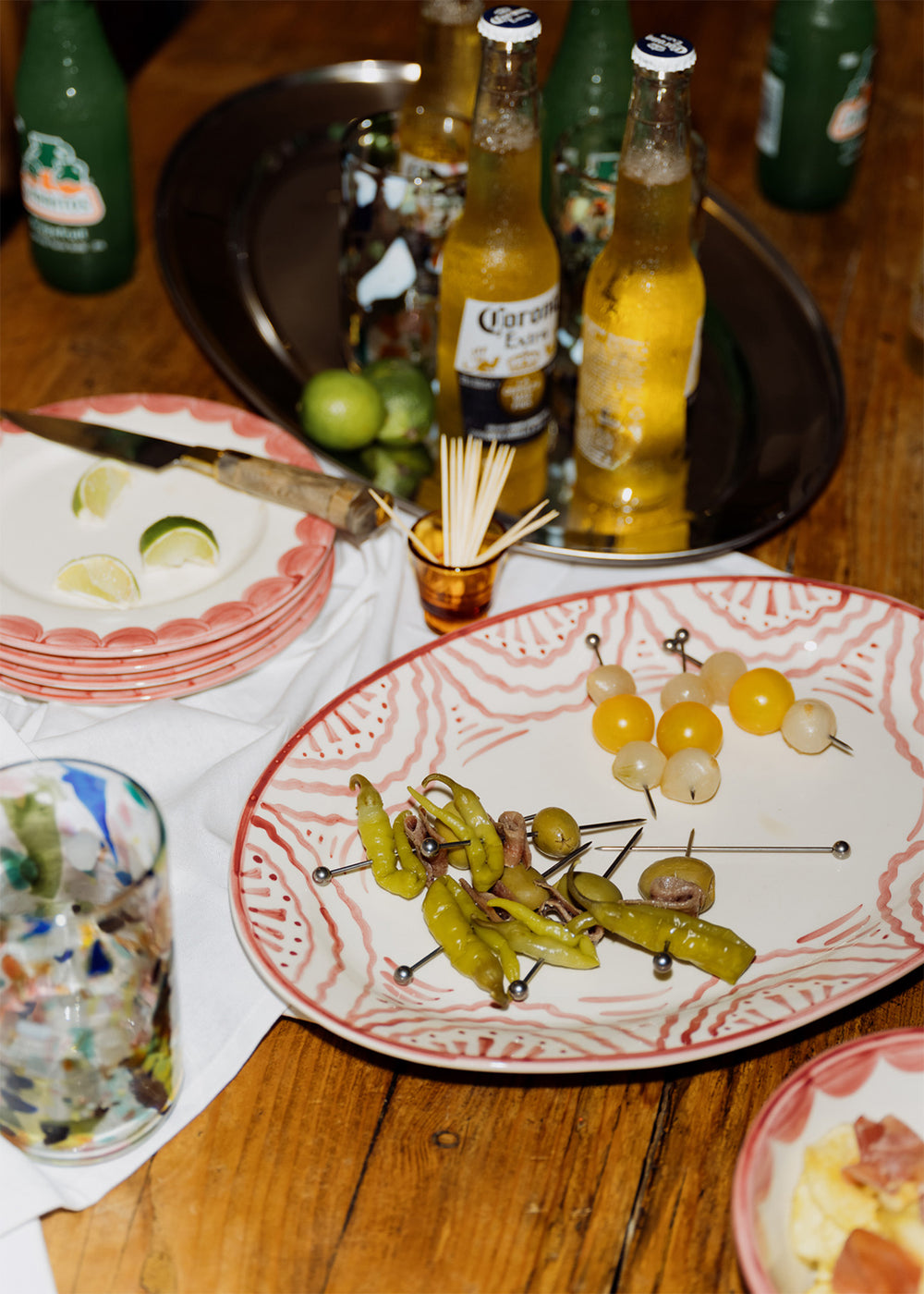 Angled view of Large Pink Platter showcasing hand-painted scalloped pink wave pattern with skewered olives and peppers on a wooden table