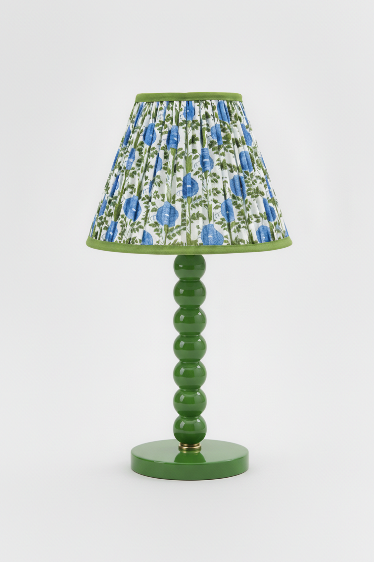 10-inch pleated blockprint empire lampshade in Araminta Blue mounted on a green ceramic lamp base with stacked spherical accents.