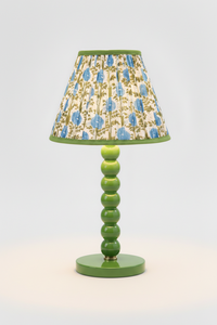 10-inch pleated blockprint empire lampshade in Araminta Blue on a green ceramic lamp base, illuminated to highlight the blue floral and green leaf design.