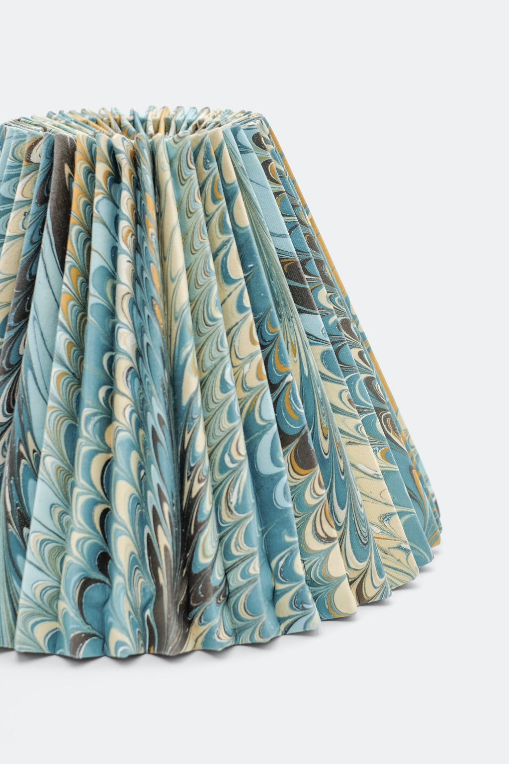 Close-up of hand-marbled pleated lampshade with blue, beige, brown swirls