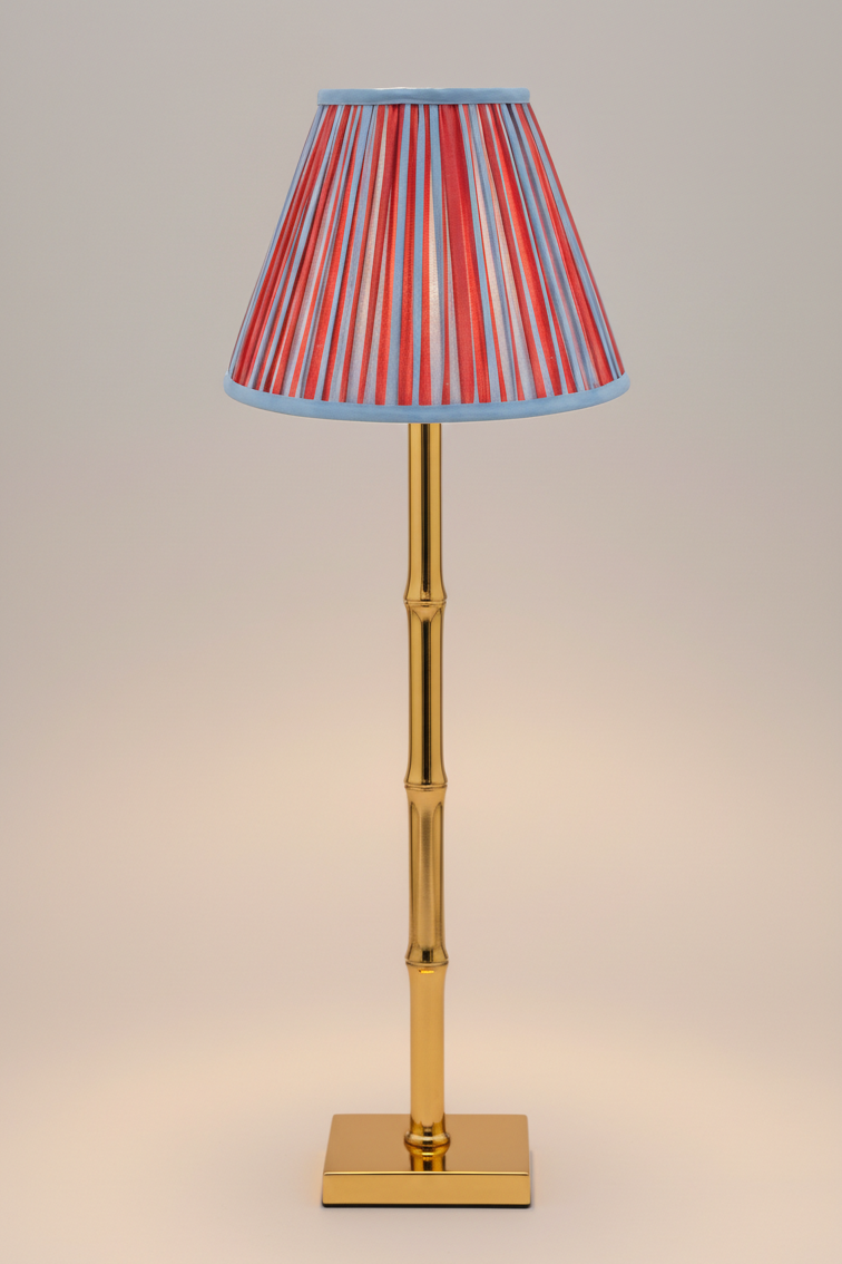 10-inch pleated blockprint empire lampshade with red and blue vertical stripes, attached to gold bamboo-style table lamp