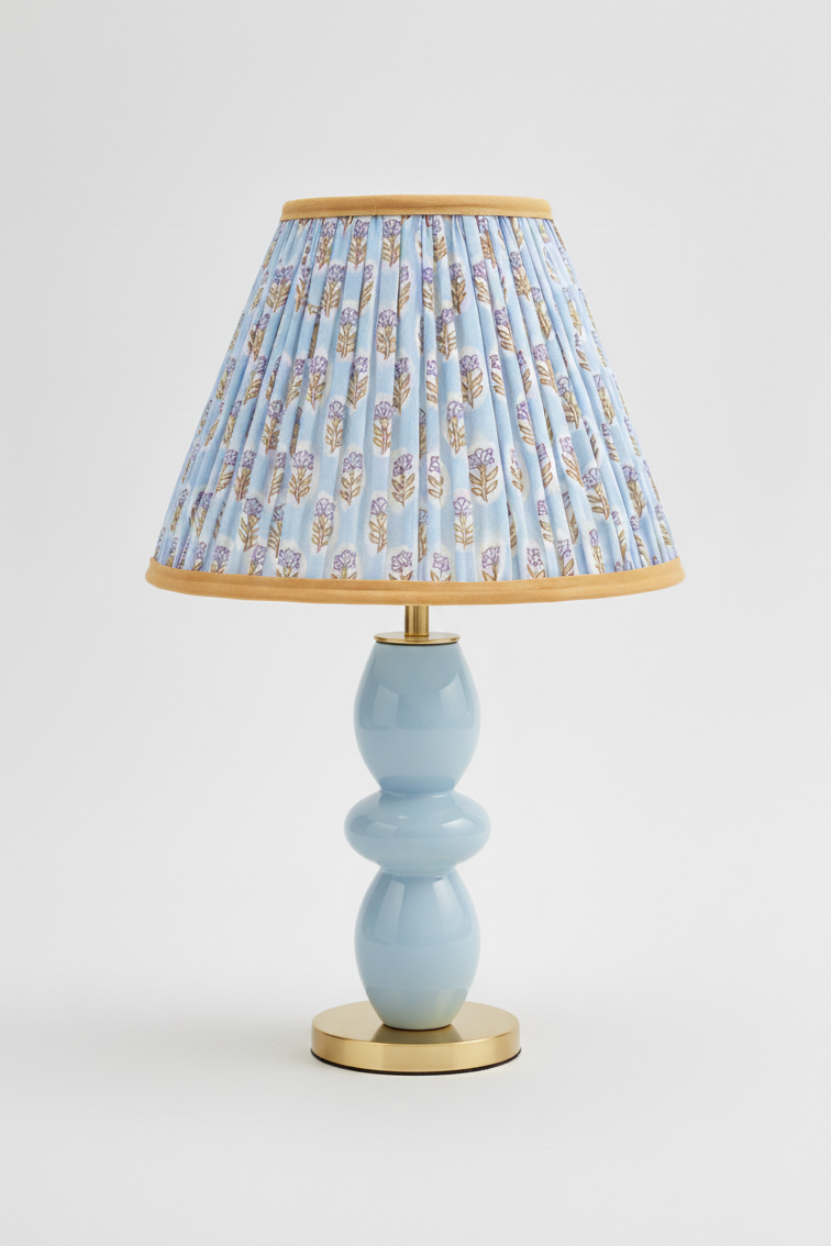 10-inch pleated blockprint empire lampshade with sky blue daisy pattern, mounted on light blue ceramic table lamp with golden base